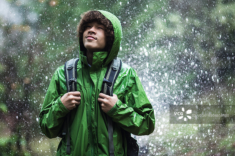 年轻男子身穿防水夹克在雨中徒步旅行图片素材