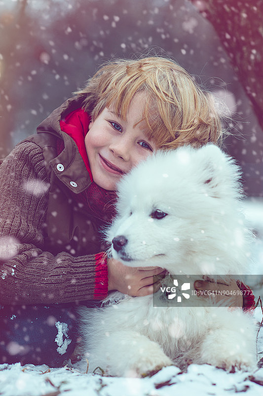 男孩和他的狗在冬天玩耍图片素材