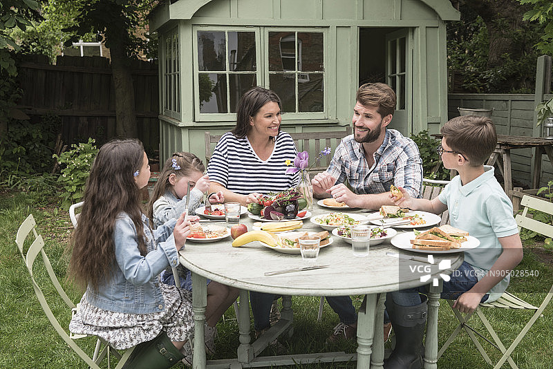 一家人在花园的桌子旁一起享用午餐图片素材
