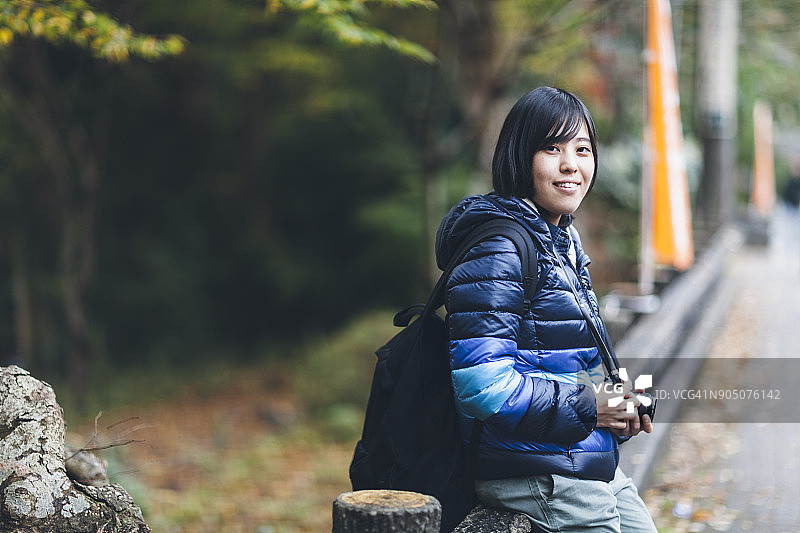 年轻女人拿着单反相机对着镜头微笑图片素材