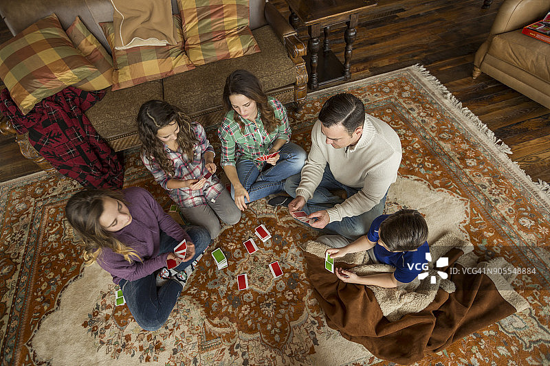 白人家庭坐在地毯上玩纸牌游戏图片素材