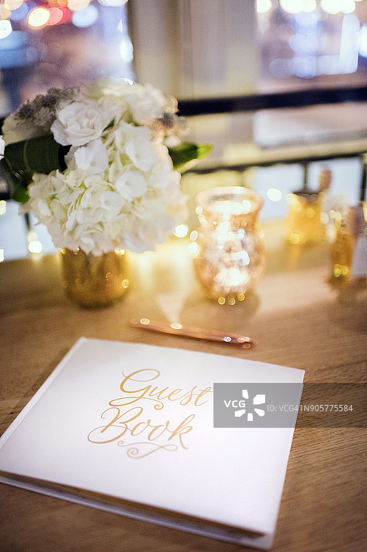 周年派对场景——木桌上的白色题词簿和玫瑰金笔图片素材