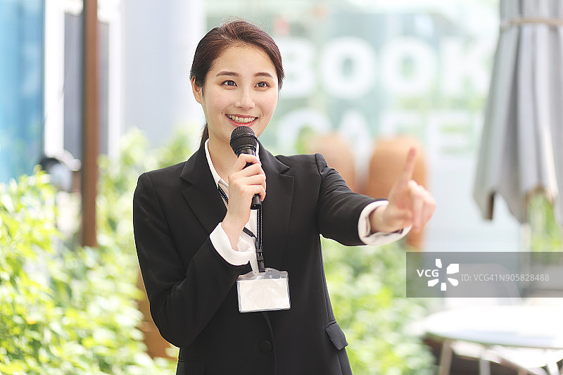 拿着麦克风并指向的商务女性图片素材