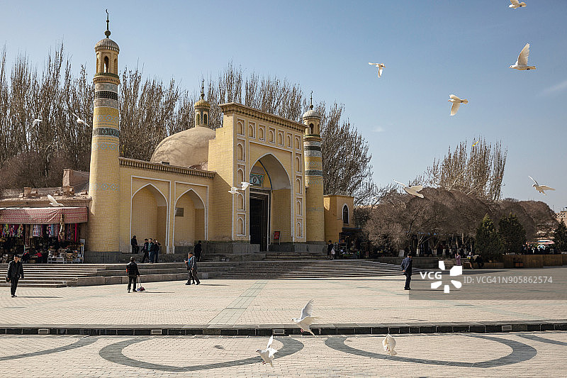 在中国喀什，飞过清真寺广场的鸽子图片素材