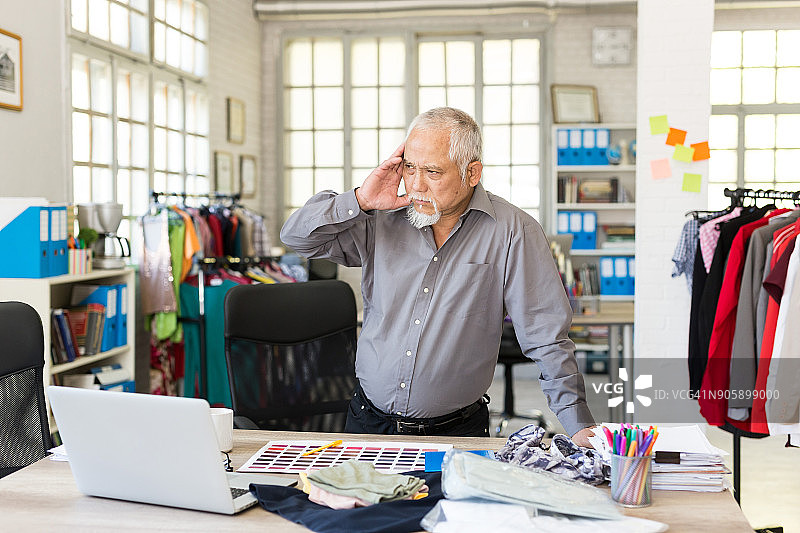 年长的亚洲商人在工作时头痛图片素材