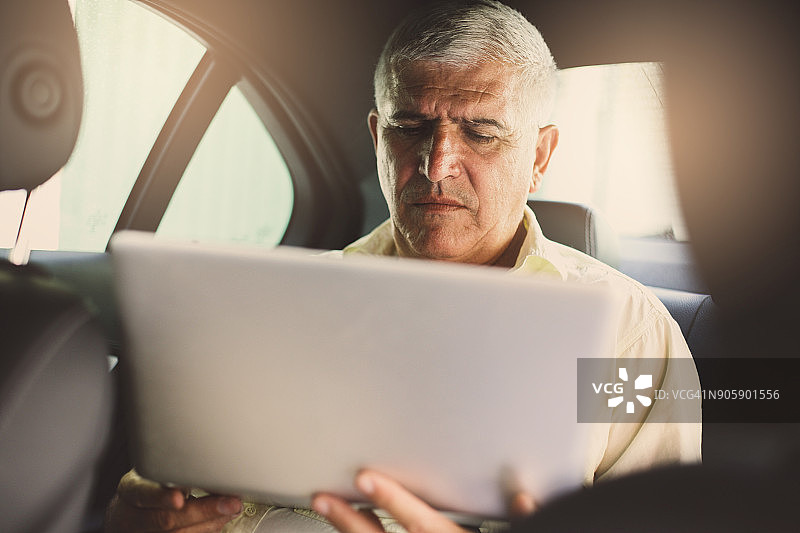 老年男人在出租车上使用电脑图片素材