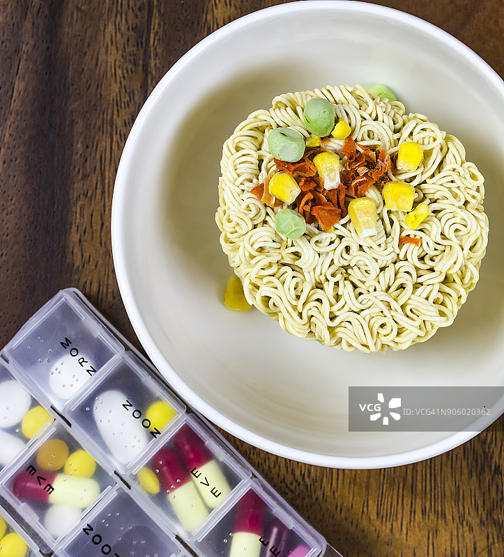 桌子上的速食杯面和药盒图片素材