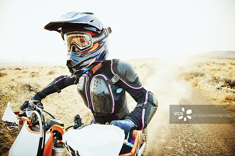 夏日傍晚，女子在沙漠道路上骑越野摩托车图片素材
