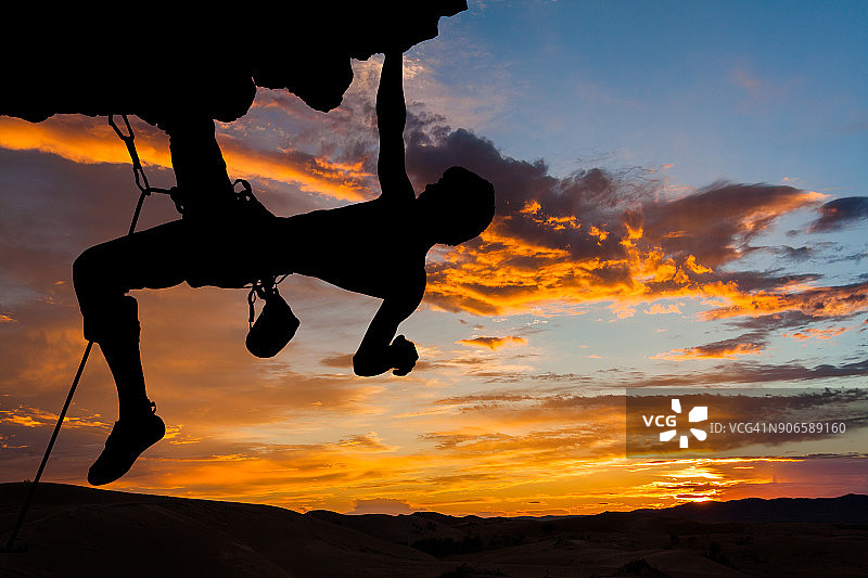 日落时分悬崖上的攀岩者剪影图片素材