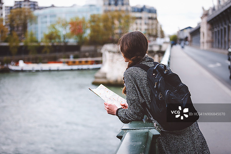 年轻女游客在埃菲尔铁塔前阅读巴黎地图图片素材
