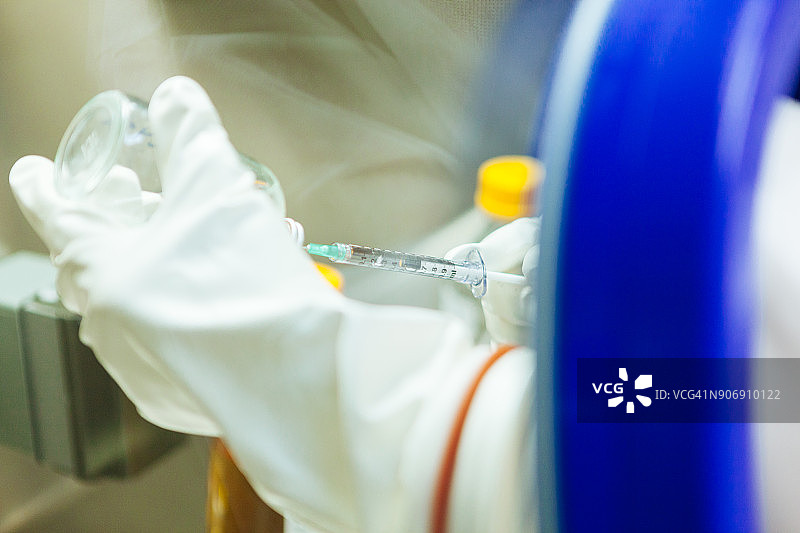 实验室助理在金属手套箱内用注射器抽取无菌液体图片素材