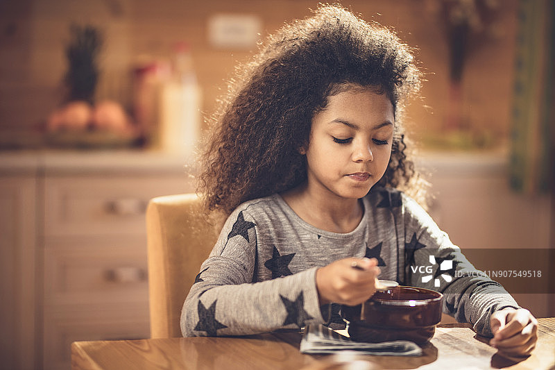 在餐桌上吃午饭的可爱非裔美国女孩图片素材