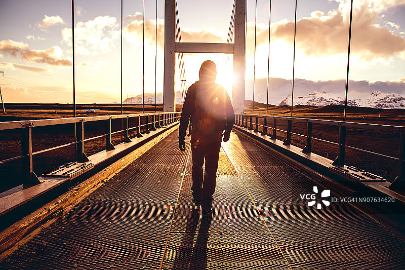独自旅行者在桥上行走，举起手臂图片素材
