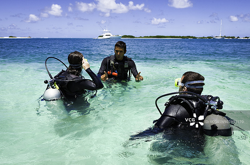 潜水教练在热带岛屿海滩指导情侣首次潜水图片素材