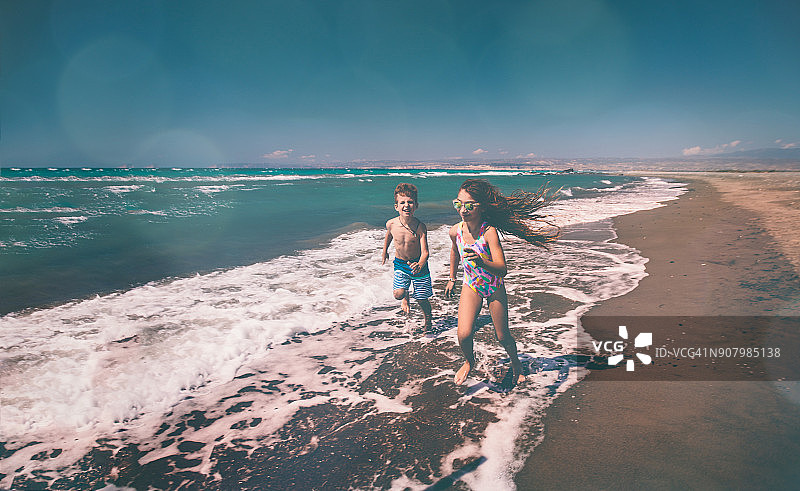 小男孩和女孩在夏季海滩上奔跑图片素材