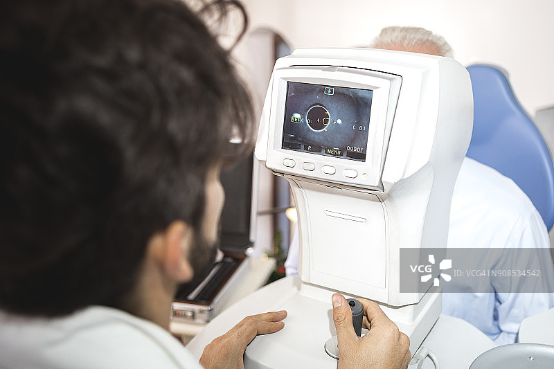 验光师用验光仪器检查老年男性图片素材