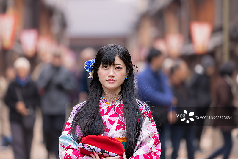身穿和服，站在传统日本小镇的年轻女子肖像图片素材