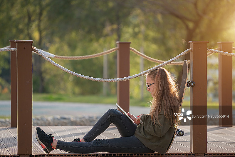 在公园使用平板电脑的快乐女孩图片素材