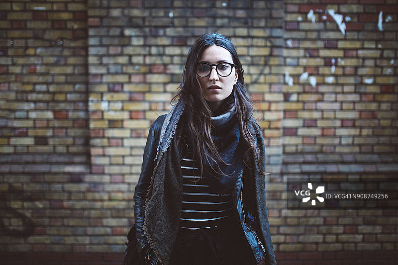 在伦敦市中心的年轻女人，站在砖墙前。图片素材