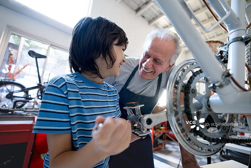 慈爱的爷爷和孙子一起修理自行车脚踏板，欢声笑语图片素材