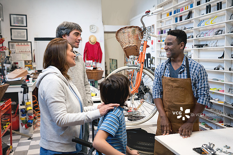 自行车店里热情的销售员接待顾客一家，为他们的儿子挑选自行车图片素材