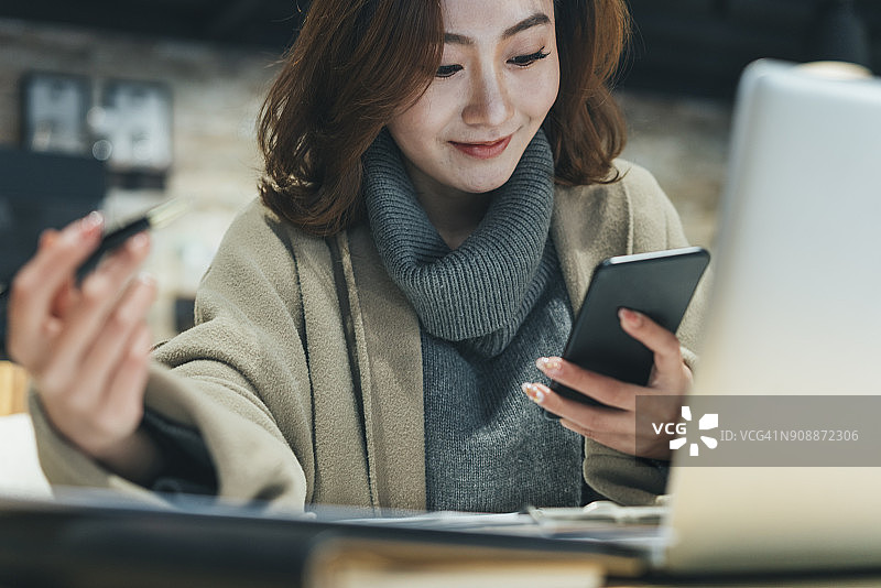 女人在咖啡店用智能手机和笔记本电脑工作图片素材