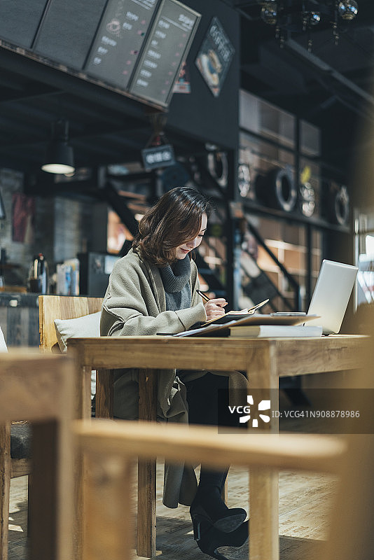 女子在咖啡店用笔记本电脑处理文书工作图片素材