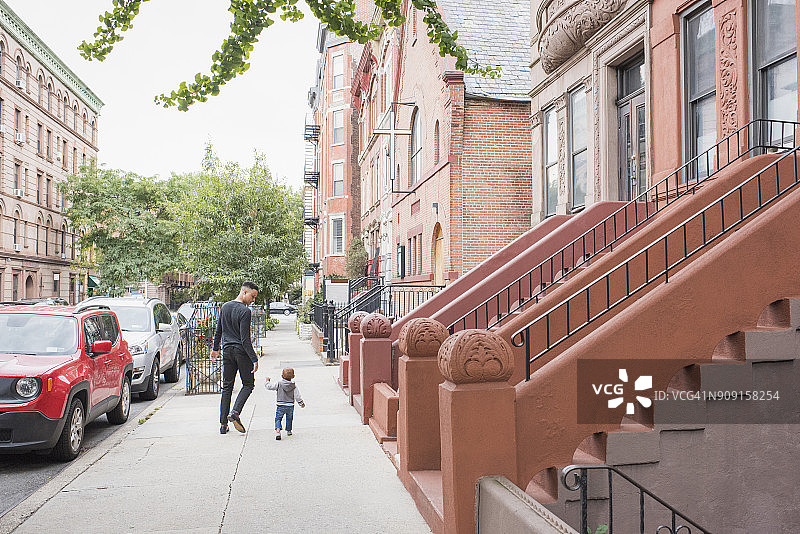 年轻母亲带着婴儿女儿在城市街区散步图片素材