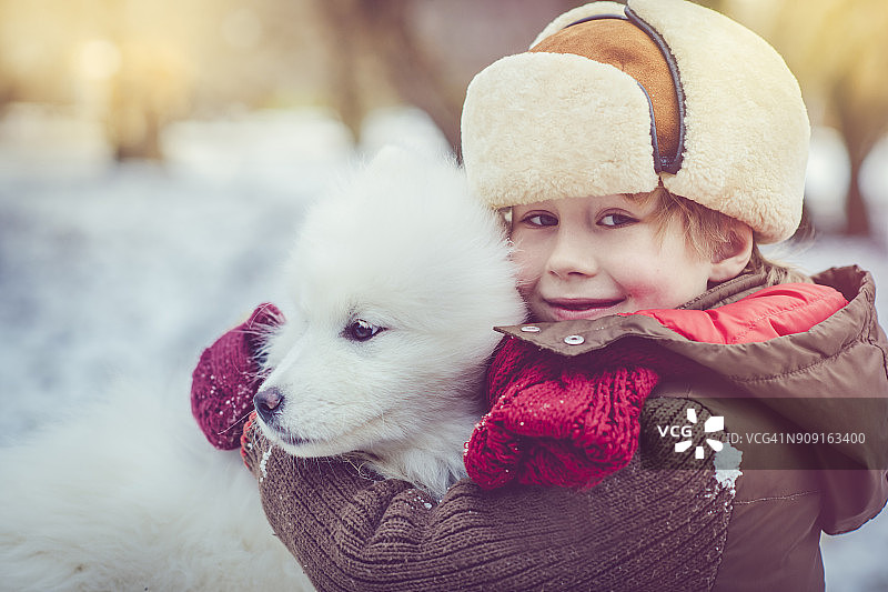 男孩和他的狗在冬天玩耍图片素材