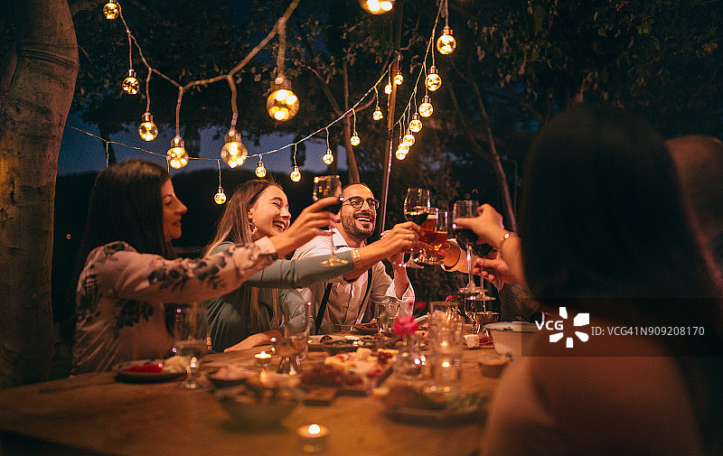 朋友们在乡村风格的晚宴上举杯畅饮啤酒和葡萄酒图片素材