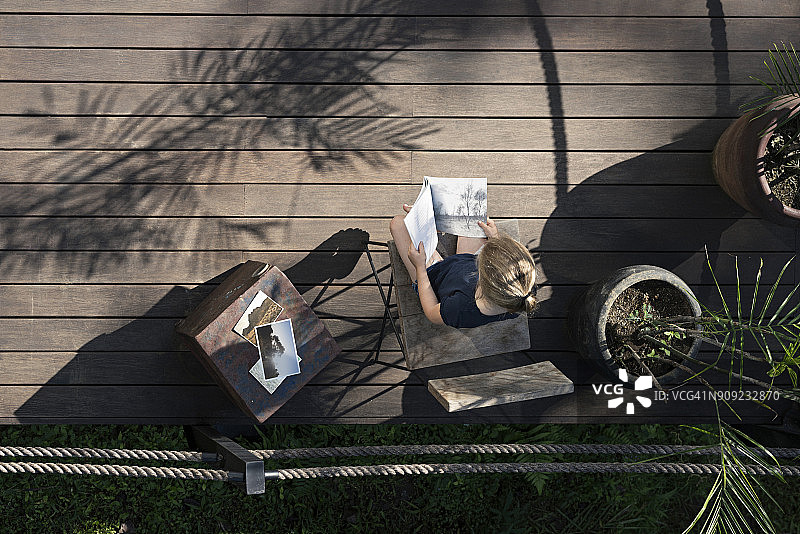 坐在阳台上看书的金发女孩图片素材