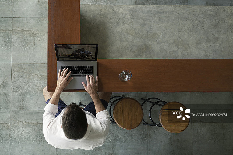 中年男人坐在厨房里使用笔记本电脑图片素材