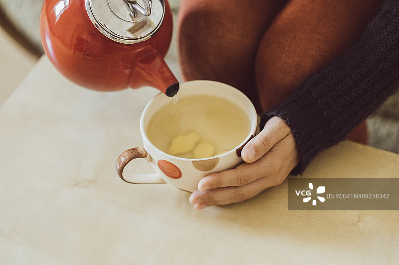 女人倒水入茶杯，加入新鲜姜末（特写）图片素材