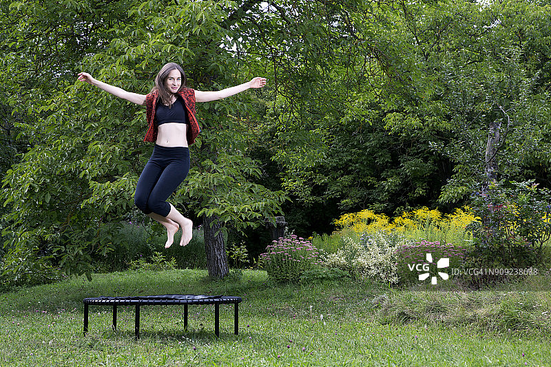在花园蹦床上跳跃的女人图片素材