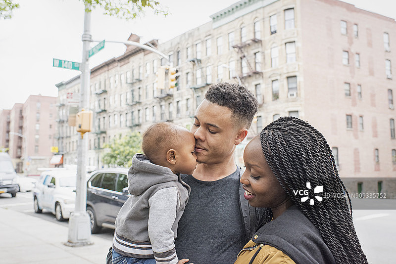 年轻的父母带着女儿在城市社区散步图片素材