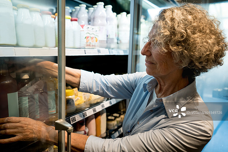 有机市场里，年长的顾客正在拿一瓶果汁图片素材