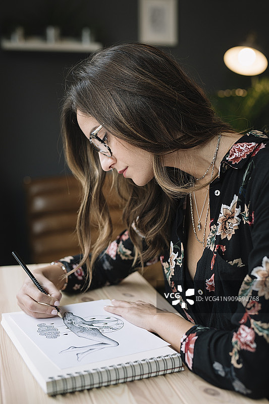 在纹身工作室的桌子上在素描本上绘画的女人肖像图片素材