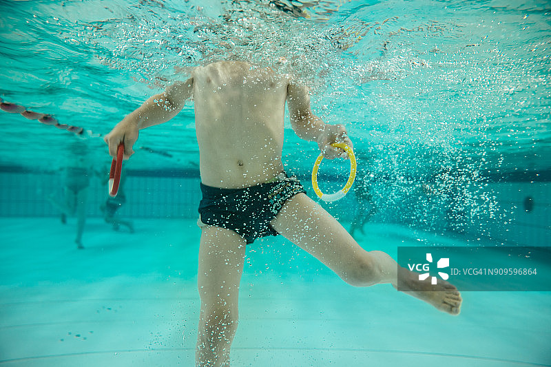 男孩在游泳池水下拿着两个游泳圈图片素材