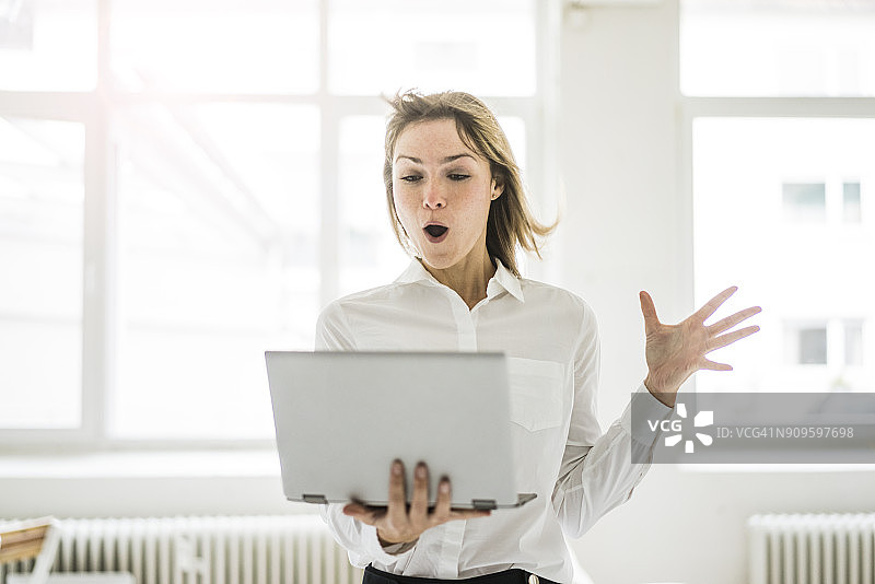 惊讶的女人拿着笔记本电脑图片素材