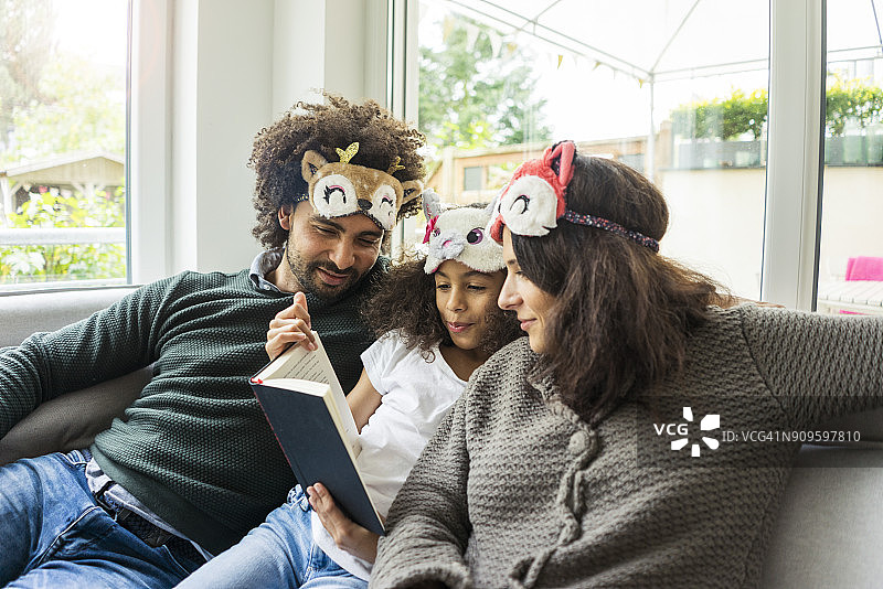 幸福家庭戴着动物面具坐在沙发上图片素材