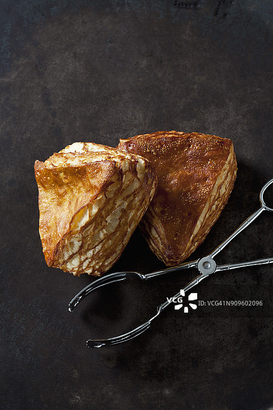 深色背景上的椒盐卷饼和糕点钳图片素材