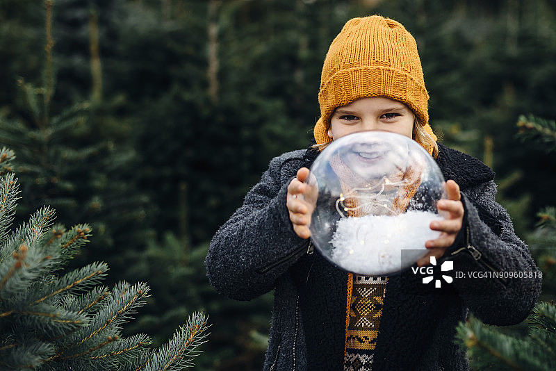 小男孩拿着一个装满雪的水晶球许愿图片素材