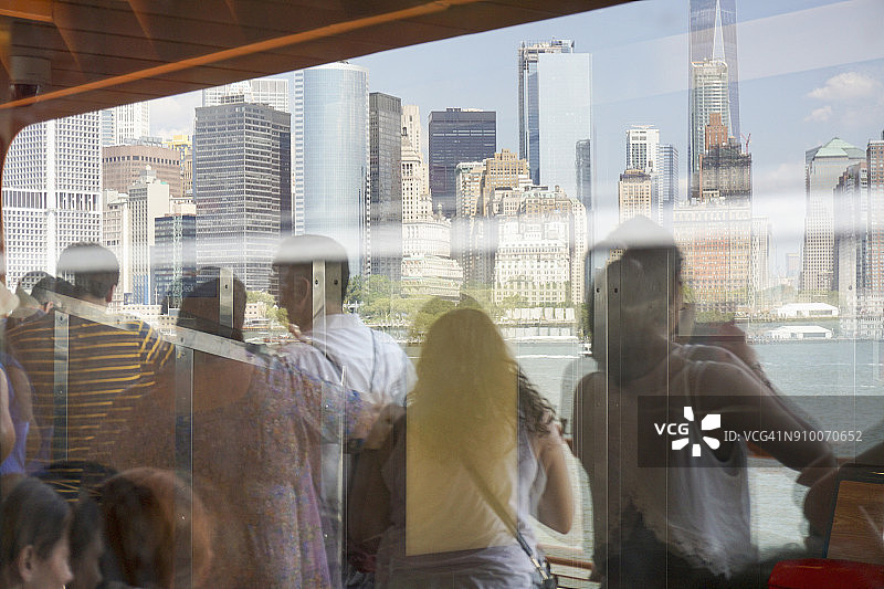 斯塔滕岛渡轮上的人们观看纽约市建筑的倒影图片素材