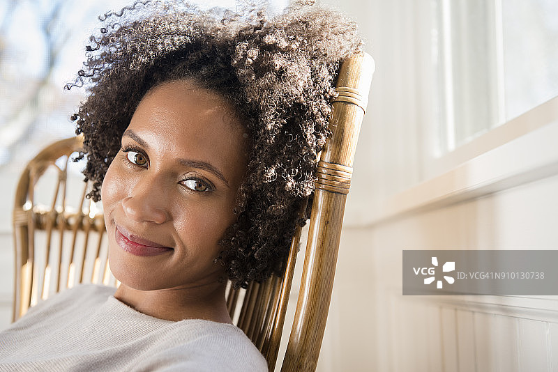 女子坐在阳光房的扶手椅上图片素材