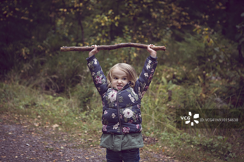 森林小路上，头顶举着大树枝的孩子图片素材