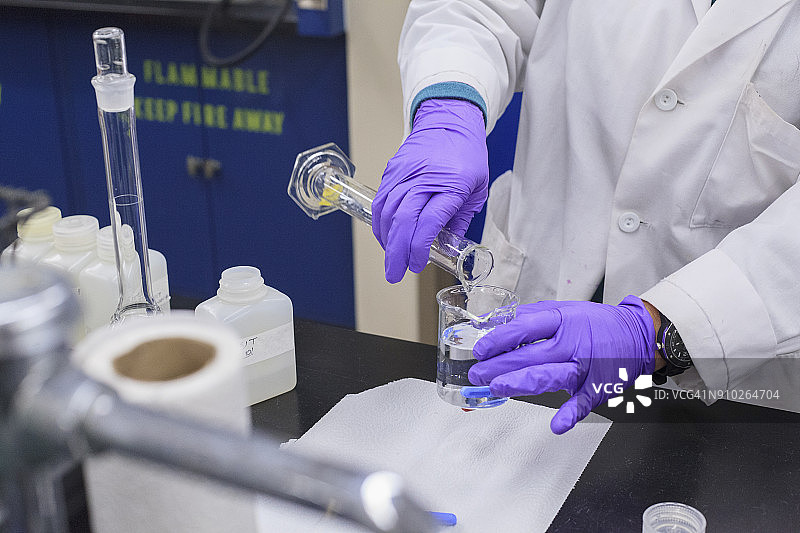 实验室技术员将量筒中的液体添加到烧杯中图片素材