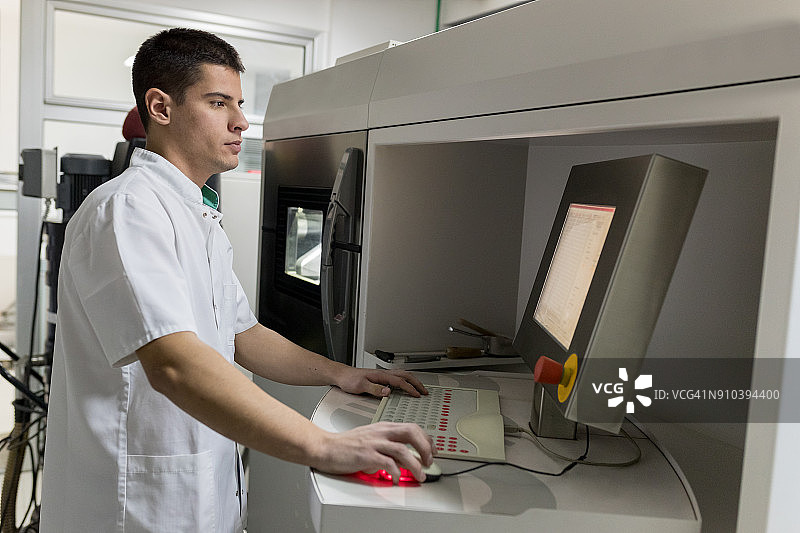 工人在控制面板上设置金属3D粉末打印机图片素材