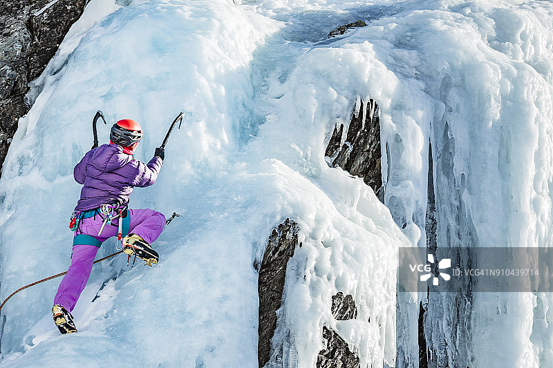 在比利牛斯山脉冰冻瀑布上攀冰的女人图片素材