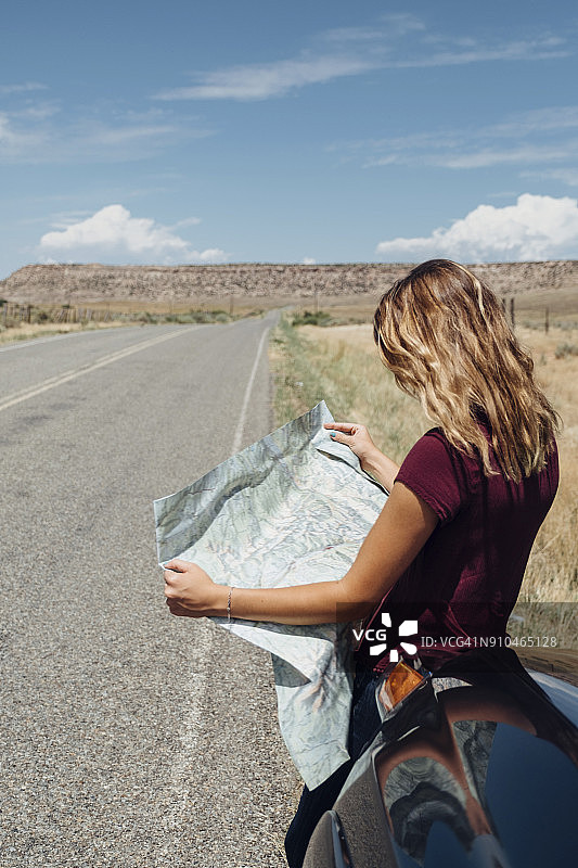 靠在车旁看地图的女人图片素材