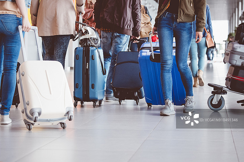 在机场航站楼拖着行李箱行走的人群图片素材